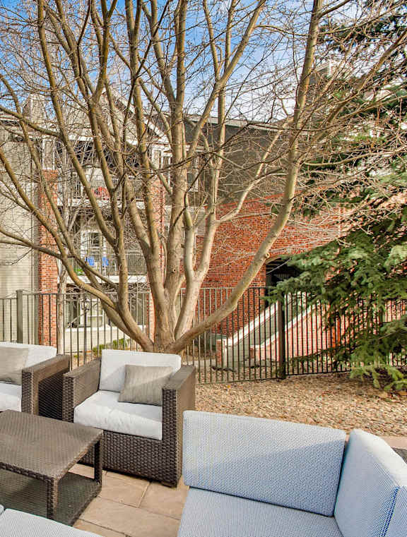A patio with a fireplace and furniture in front of a building.