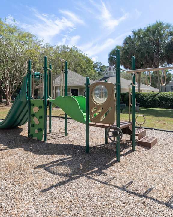 A playground with a green slide and a yellow and green play structure.