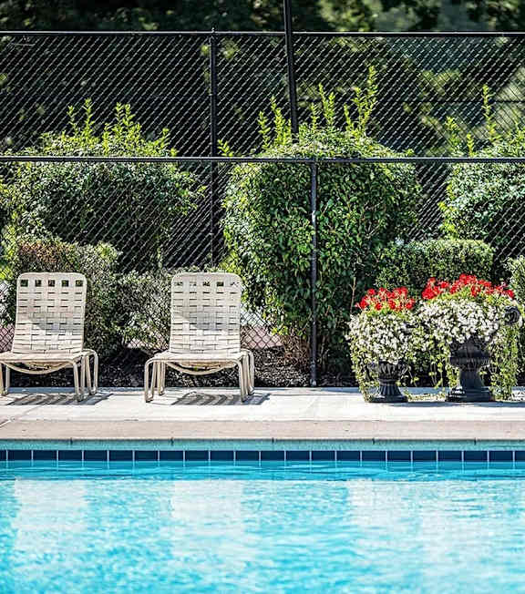 A pool surrounded by a black fence with blue umbrellas.