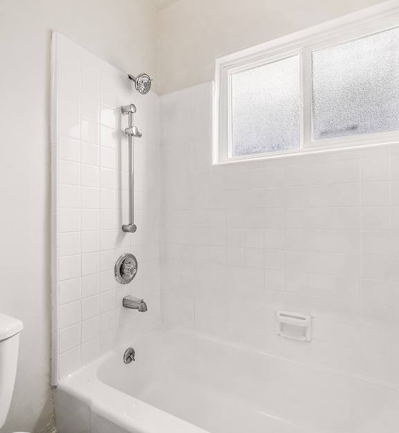 A white bathroom with a tub, shower, and toilet.