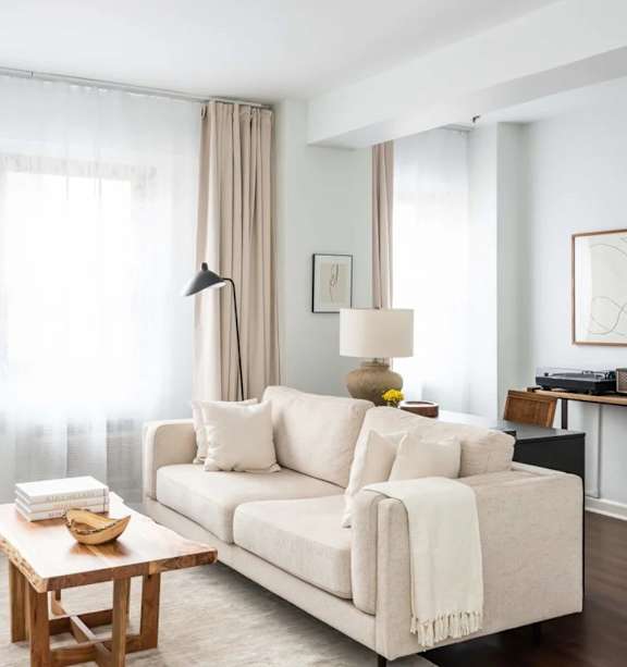A living room with a white couch, a wooden coffee table, and a chair.