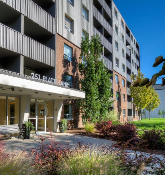 a large apartment building with balconies and a grassy area in front of it