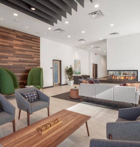 a lobby with chairs and a table and a fireplace