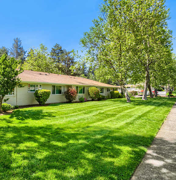 A house with a green lawn and trees in the background.