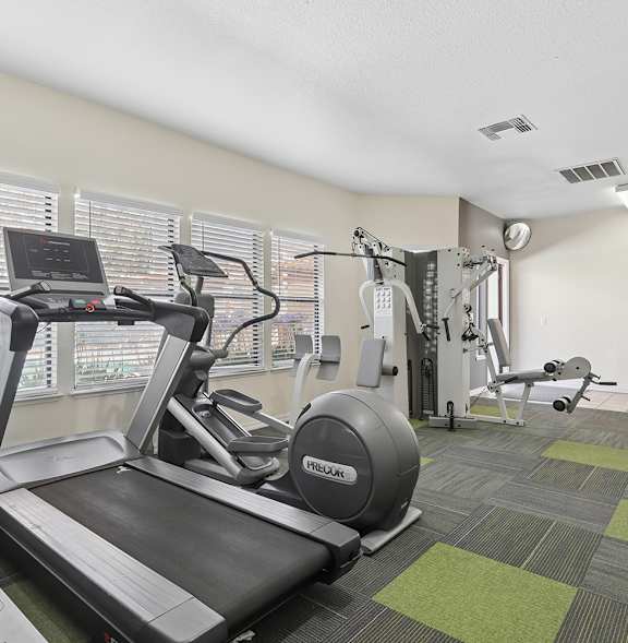 A treadmill is in a gym with a green and grey floor.