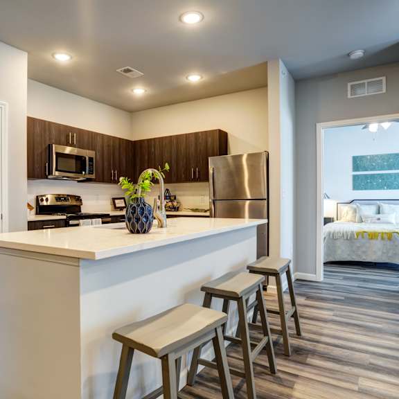 A kitchen with a white counter top and wooden floors.