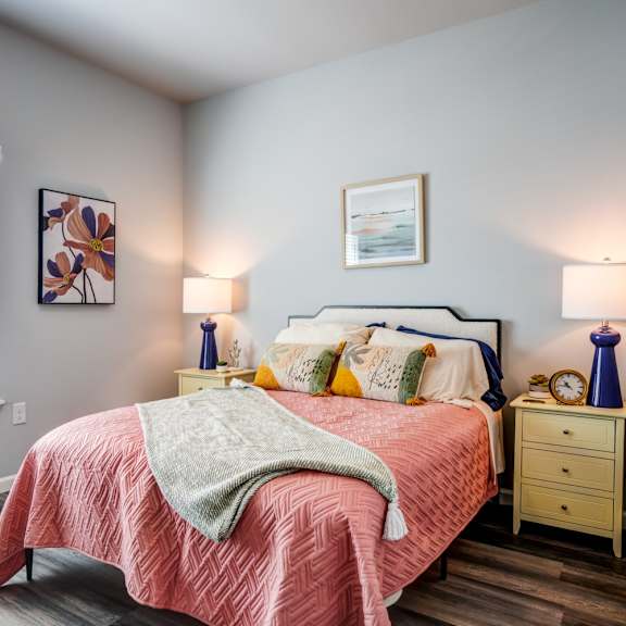A bedroom with a bed, nightstands, and a window.