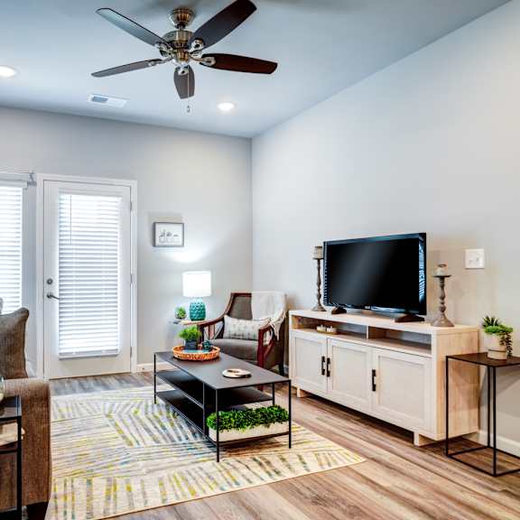 A living room with a ceiling fan, a couch, a coffee table, and a television.