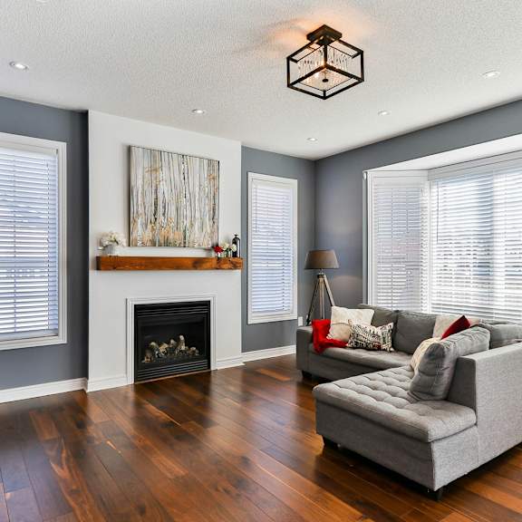 A living room with a grey couch and a fireplace.