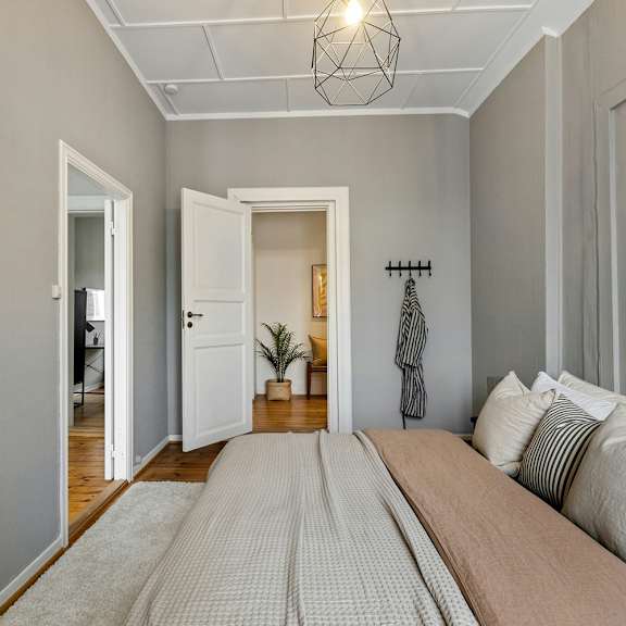 A bedroom with a bed, pillows, and a framed picture on the wall.