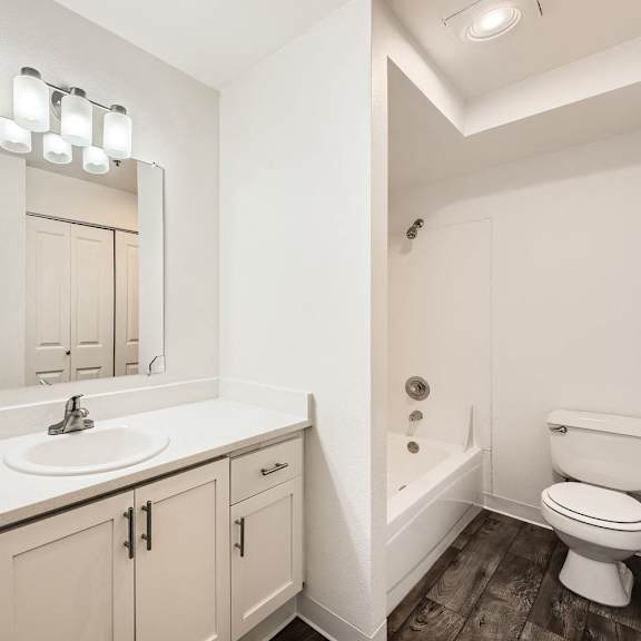 A white bathroom with a sink, mirror, and toilet.