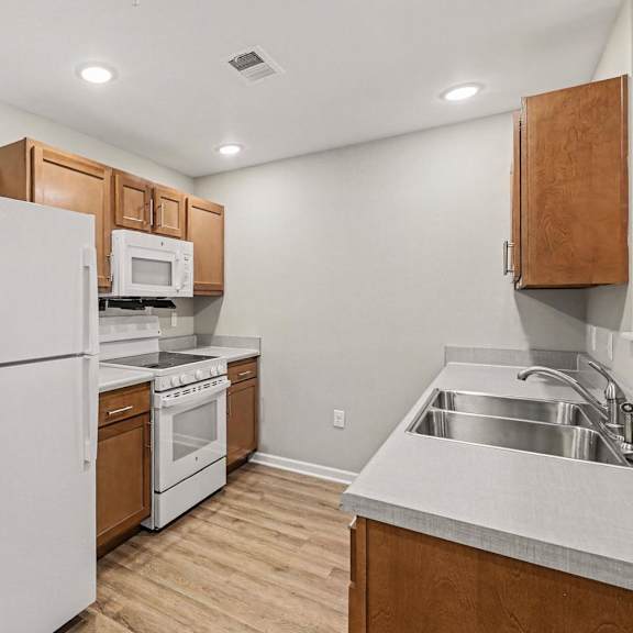 A kitchen with white appliances and wooden cabinets.