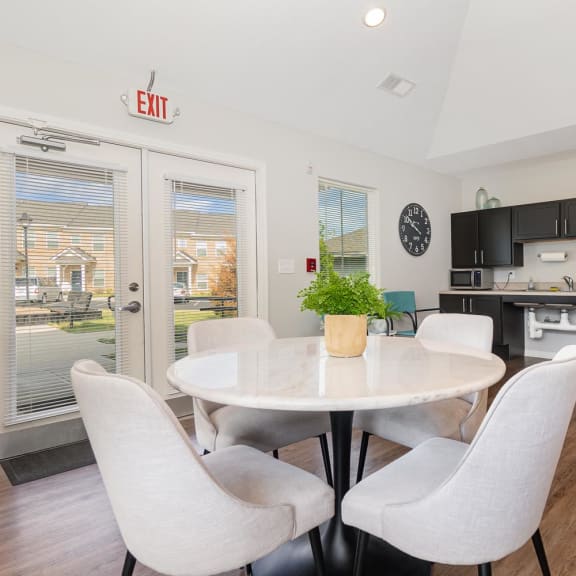 a dining area with a table and chairs and a kitchen in the background