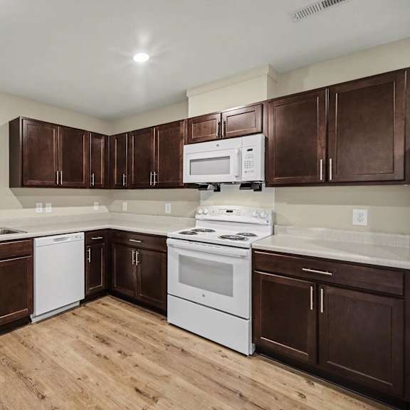 A kitchen with brown cabinets and white appliances.