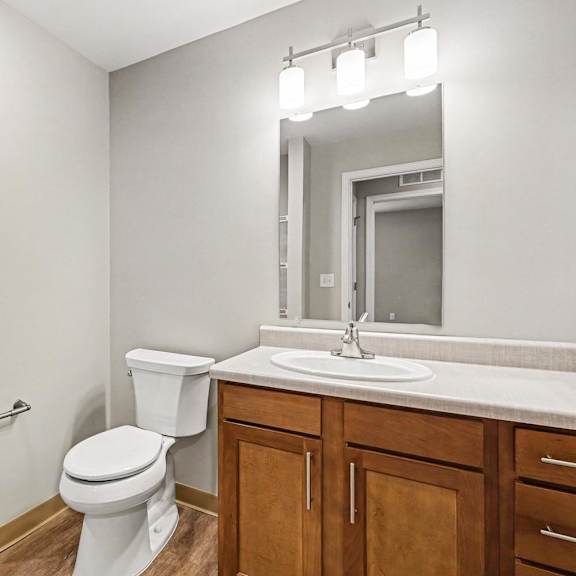 A white toilet sits in a bathroom next to a sink and a mirror.