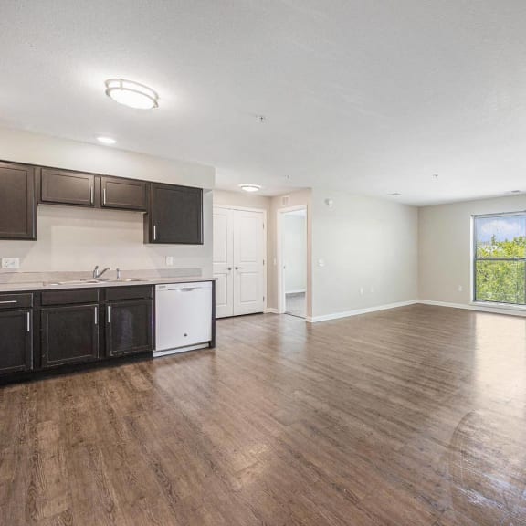 an empty living room and kitchen with wood flooring