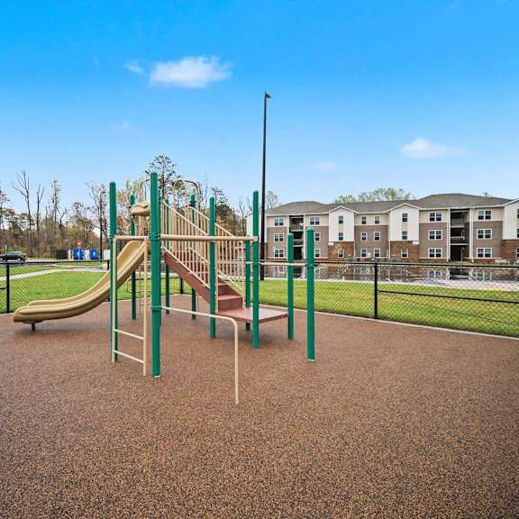 A playground with a slide and a green pole.
