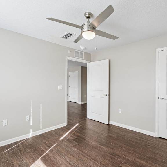 A room with a ceiling fan and a door.