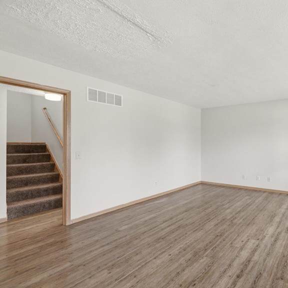 A room with wooden floors and a staircase leading to another room.