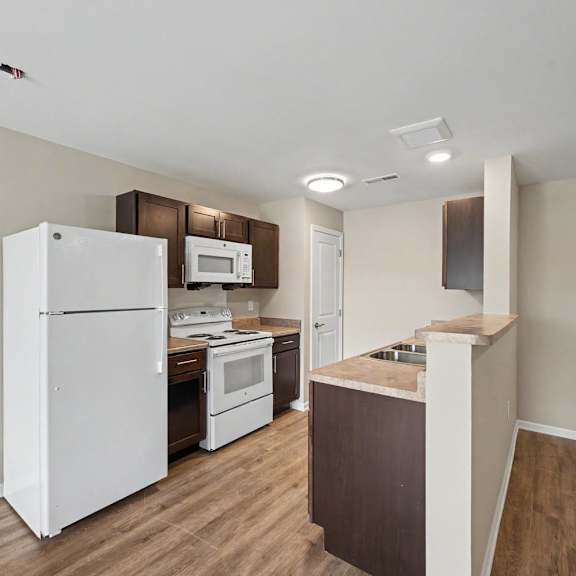 A kitchen with white appliances and wooden cabinets.