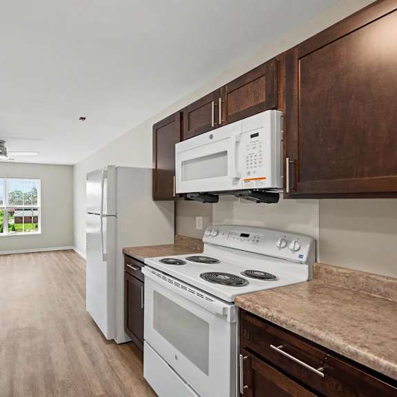 A kitchen with white appliances and wooden cabinets.