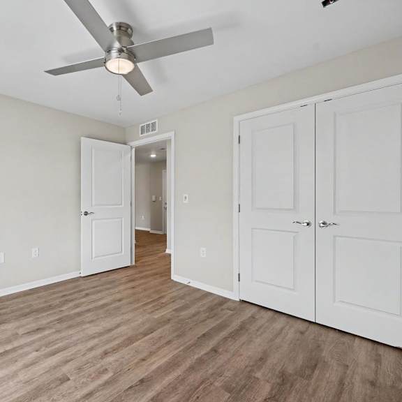 A room with a ceiling fan and wooden flooring.