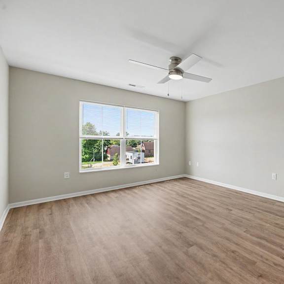 Empty room with a window and a ceiling fan.