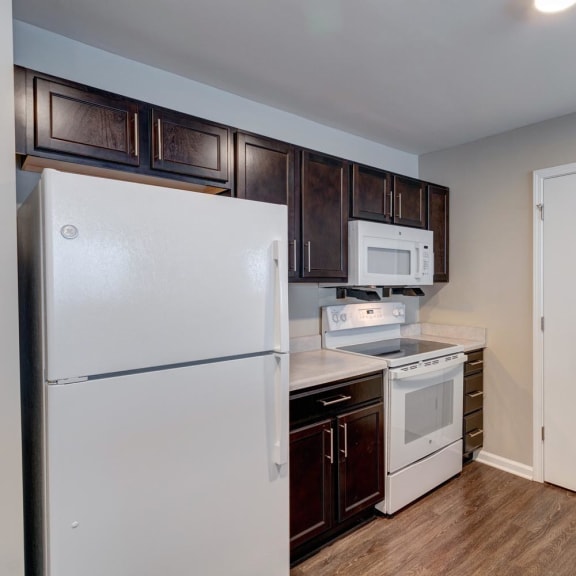 a kitchen with dark wood cabinets and white appliances
