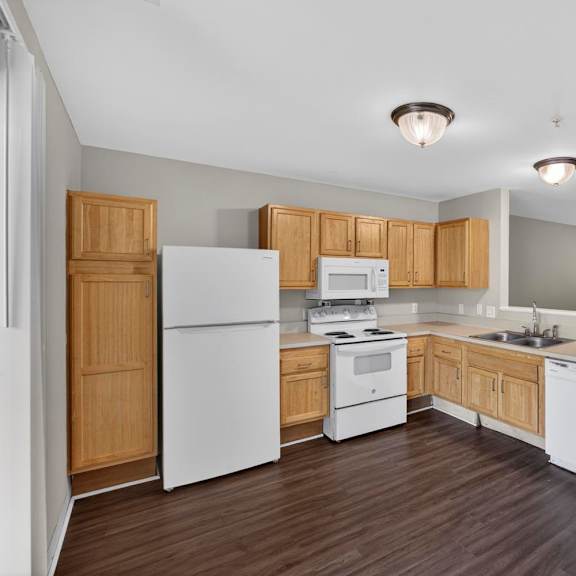 A kitchen with white appliances and wooden cabinets.