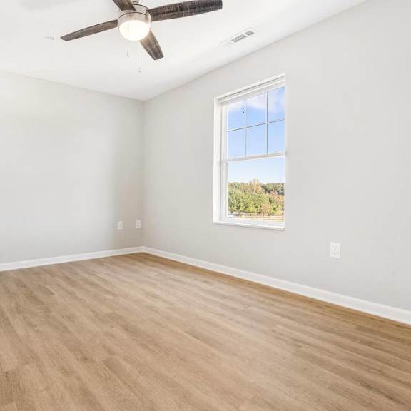 an empty living room with hardwood floors and a ceiling fan