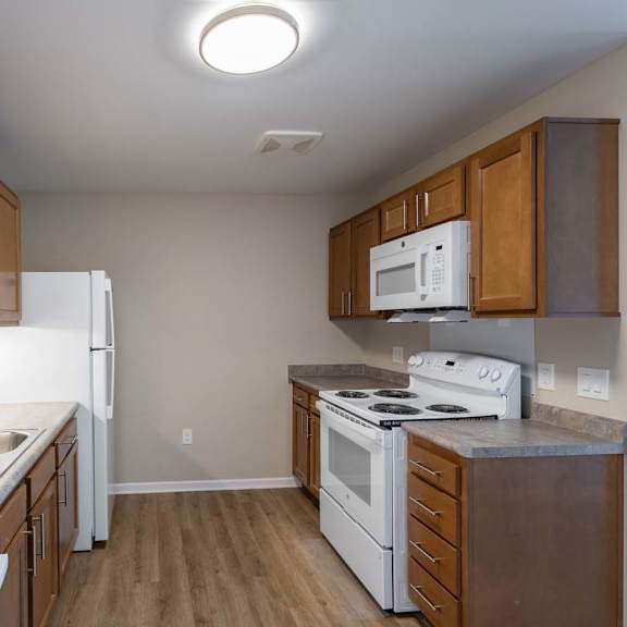 A kitchen with white appliances and wooden cabinets.