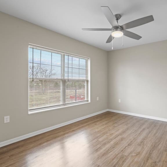 an empty living room with a ceiling fan and a window