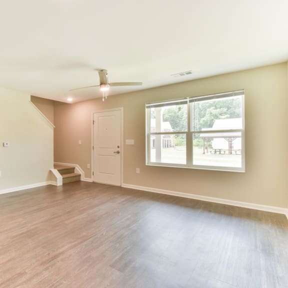 an empty living room with a ceiling fan and a window
