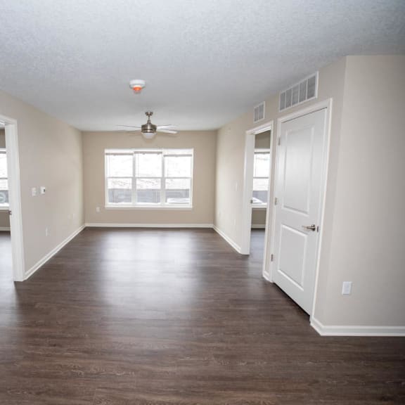 an empty living room with wood floors and a window