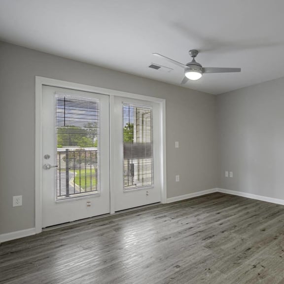 an empty living room with a ceiling fan and a window