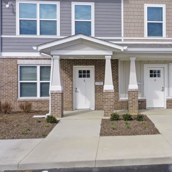 the front of a brick house with white doors and a sidewalk