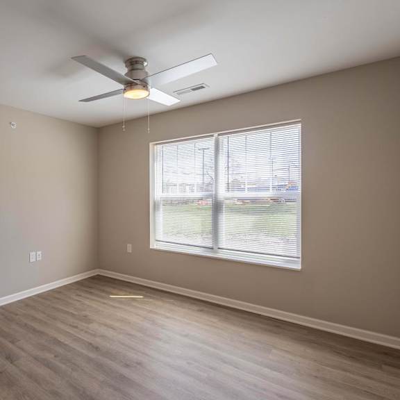 A room with a ceiling fan and a window.