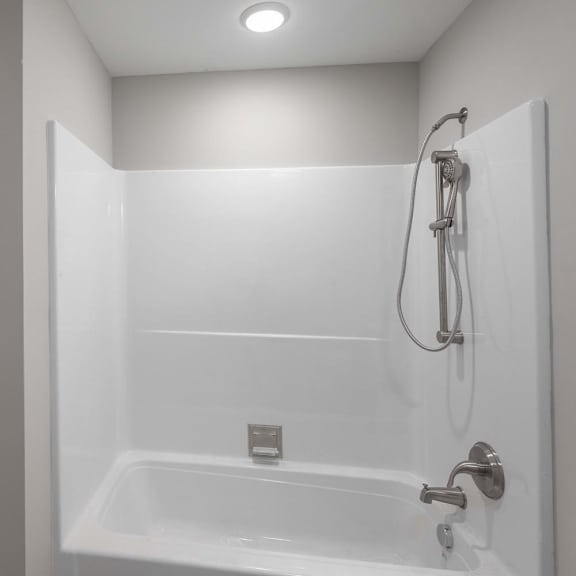 A white bathroom with a microwave and a bathtub.