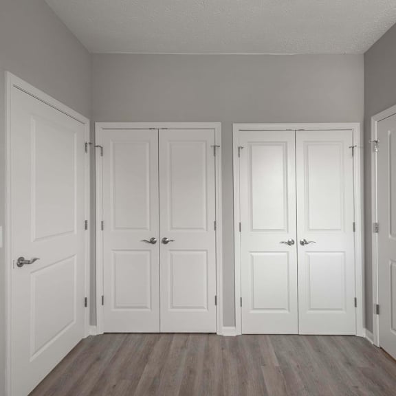 A room with four white doors and wooden floors.