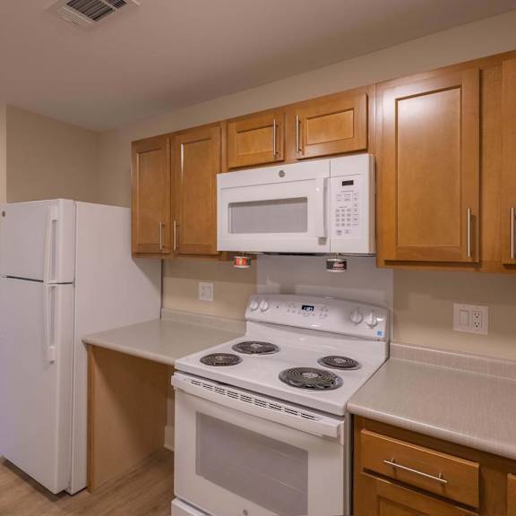 A kitchen with a white refrigerator, white microwave, and white stove.