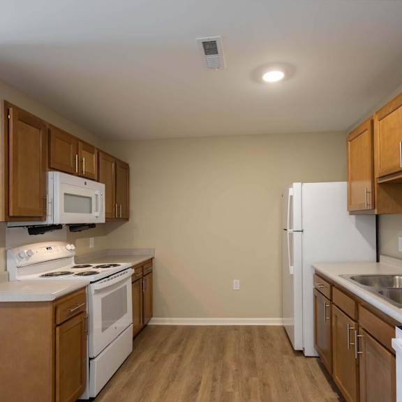 A kitchen with white appliances and wooden cabinets.