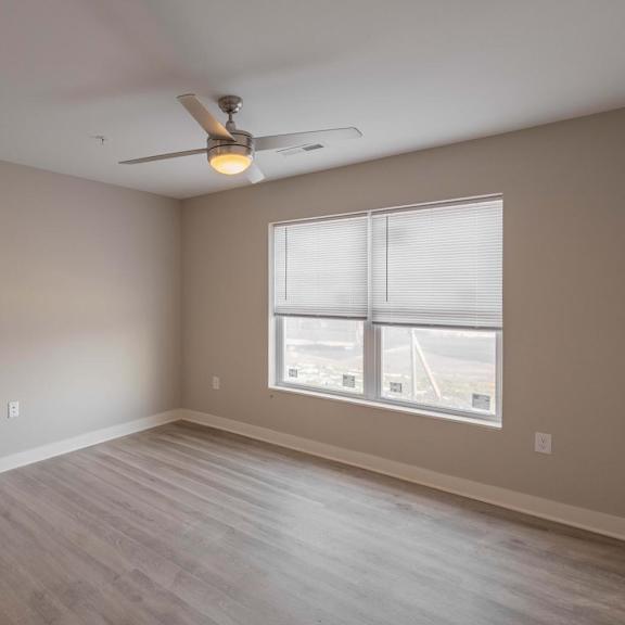 A room with a ceiling fan and a window with blinds.