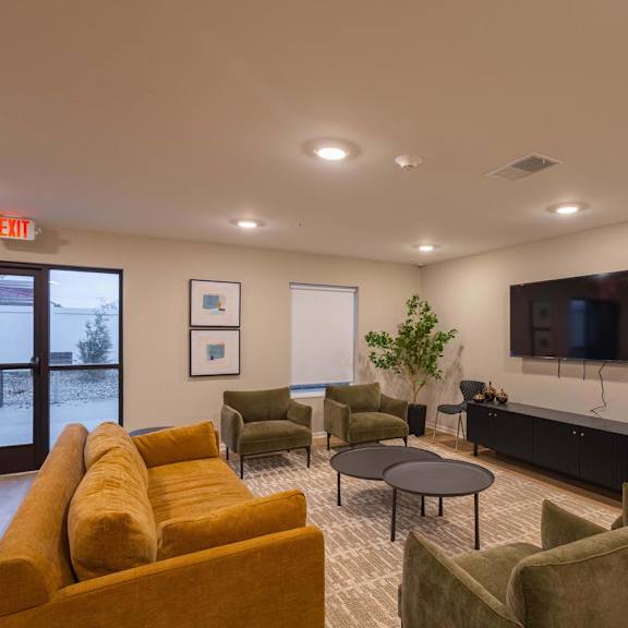 A living room with a yellow couch and a flat screen TV.