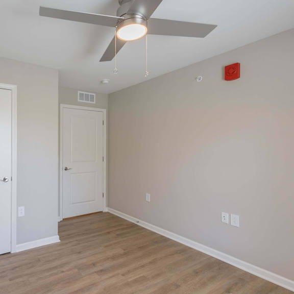 A room with a ceiling fan and two doors.