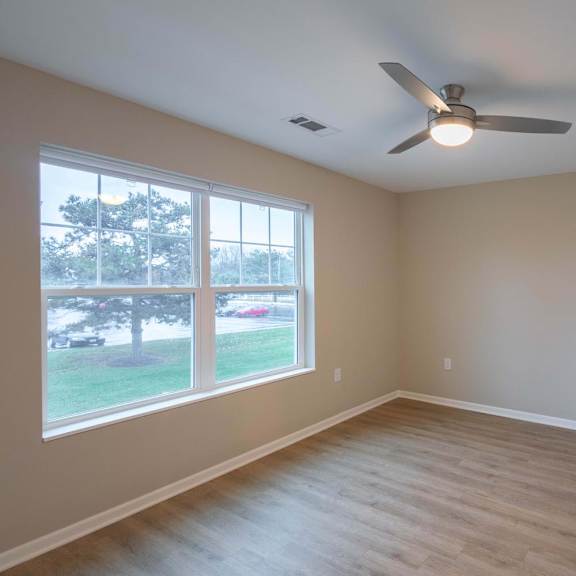 A room with a ceiling fan and a large window.