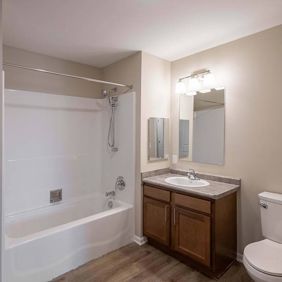 A white bathtub with a shower head and a white toilet in a bathroom.