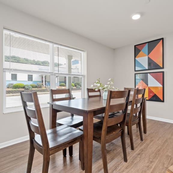 a dining room with a wooden table and chairs and a large window
