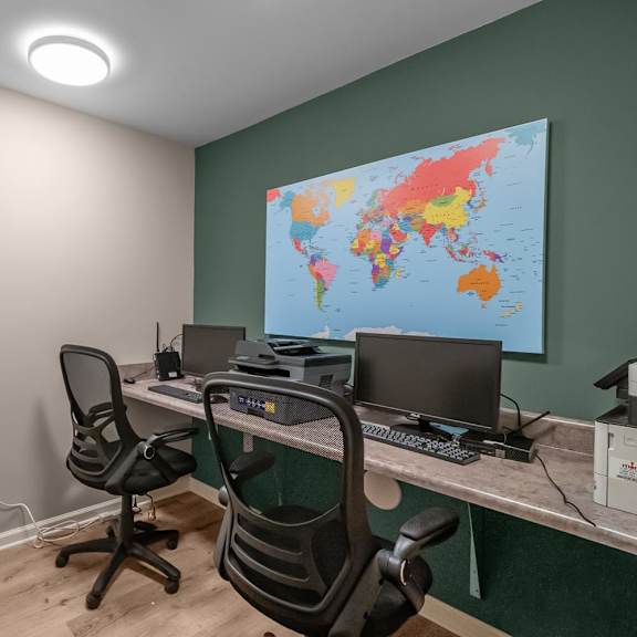 A room with two chairs and a desk with a laptop and a monitor.