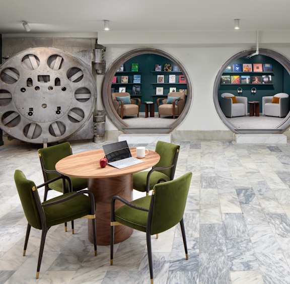 A room with a table and chairs in front of a wall with circular windows.