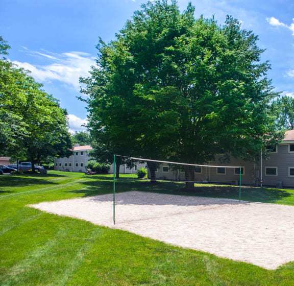 a volleyball court in a grassy area with a house in the background At Williamsburg Estates In Harrisburg, PA.